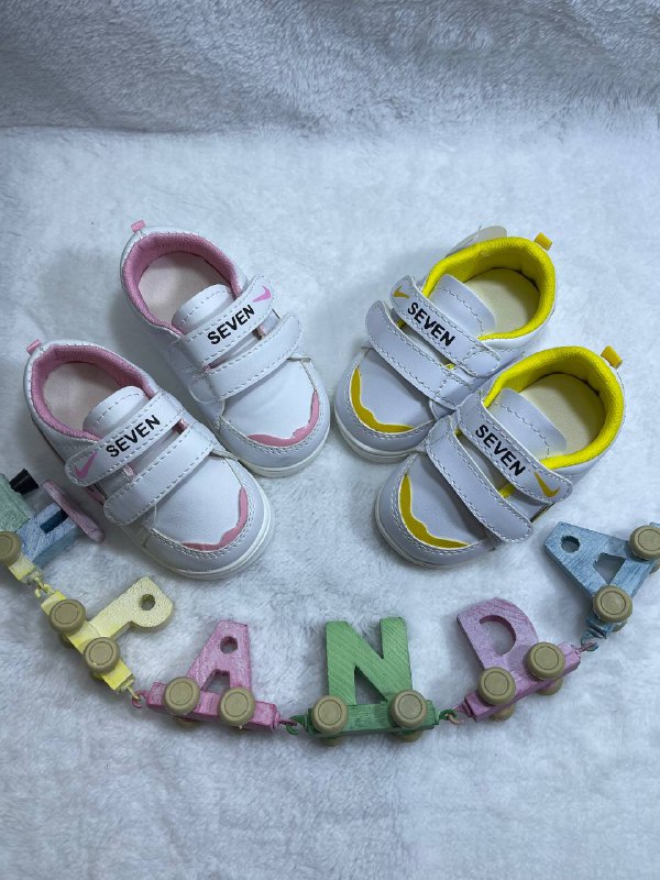 تصویر > آقای جلیلی: 28/کتانی اسپرت بچگانه سوتی نایکی (Nike) مدل SEVEN > آقای جلیلی: این کتانی بچگانه نایکی با طراحی مینیمال و ترکیب رنگی بسیار شاد سفید و زرد، انتخابی ایده‌آل برای استایل‌های تابستانی و بهاری کودکان است. مدل SEVEN با تمرکز بر راحتی و وزن بسیار سبک طراحی شده تا از خستگی پای کودک در هنگام فعالیت‌های طولانی جلوگیری کند. رویه این کفش از چرم صنعتی مرغوب با دوخت‌های تمیز ساخته شده و آستر داخلی زرد رنگ آن علاوه بر زیبایی، لطافت خاصی برای پوست پا فراهم می‌کند. سیستم بستن این کفش به صورت دو چسب پهن (Double Strap) است که پوشیدن آن را برای کودکان بسیار آسان کرده و باعث می‌شود کفش به خوبی در پا محکم شود. لوگوی نایکی به صورت دو رنگ در کناره‌ها و روی چسب کفش، اصالت طرح را به نمایش می‌گذارد. 4